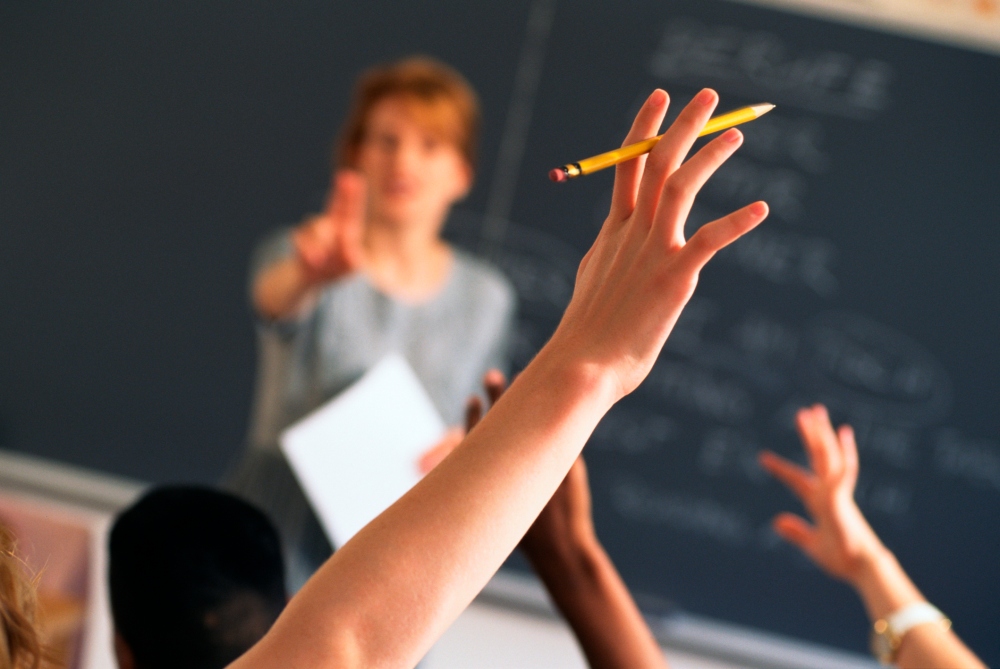 Teacher pointing to raised hands in classroom
